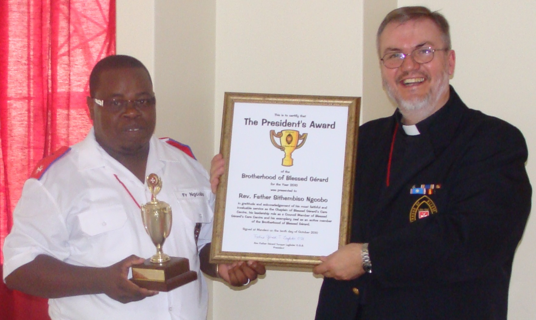 Father Gérard presenting the President’s Award certificate to Father Sithembiso Ngcobo, who holds the trophy